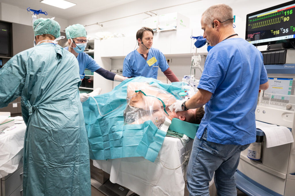 Patient Max trägt einen Brustkorb-Attrappe aus Kunststoff, die vom Notfallteam beatmet wird.