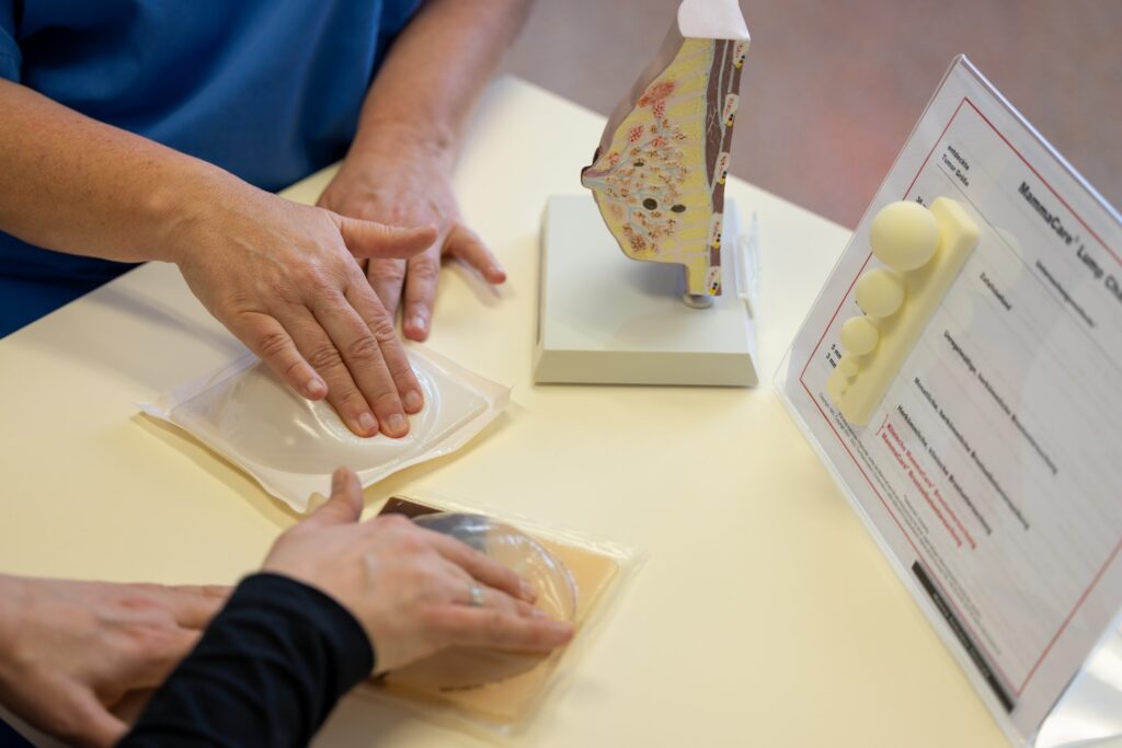 zwei unterschiedliche hände drücken tief in zwei silikonbrust-modelle